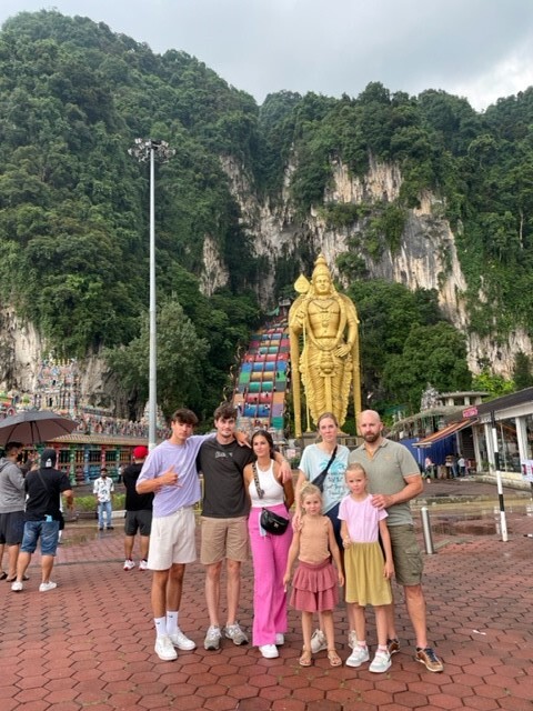 Gezinsavontuur bij de Batu Caves in Maleisië Gezin met kinderen voor de kleurrijke trappen van de Batu Caves in Maleisië